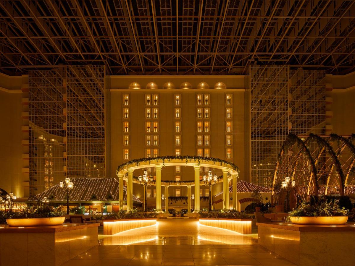 Отель Grand Nikko Tokyo Bay Maihama Ураясу Экстерьер фото The photo shows the interior of a luxurious hotel or resort. It features a spacious atrium with elegant architecture, including a high ceiling supported by beams. The area is well-lit with warm, ambient lighting that highlights various design element