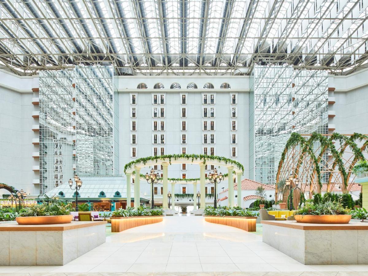 Отель Grand Nikko Tokyo Bay Maihama Ураясу Экстерьер фото The photo shows a spacious atrium or indoor area of a building, likely a hotel or resort. The architecture features large glass panels overhead, allowing for natural light to flood the space. There are elegant decorative elements, such as arches ador