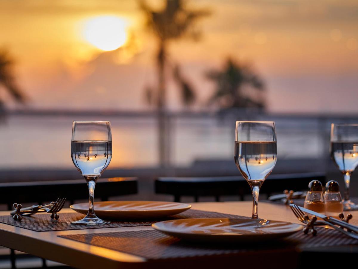 Отель Grand Nikko Tokyo Bay Maihama Ураясу Экстерьер фото The photo depicts a picturesque dining setting at sunset. In the foreground, there are two elegantly arranged tables, each set with plates and glasses filled with water. The glasses are crystal clear, reflecting the warm colors of the sunset. Behind 