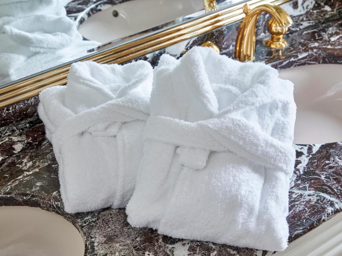Отель Grand Nikko Tokyo Bay Maihama Ураясу Экстерьер фото The photo shows two white bathrobes neatly folded and placed on a marble surface, likely in a luxurious bathroom setting. The bathrobes have a simple, classic design with belts tied around them. In the background, there appears to be a decorative mir