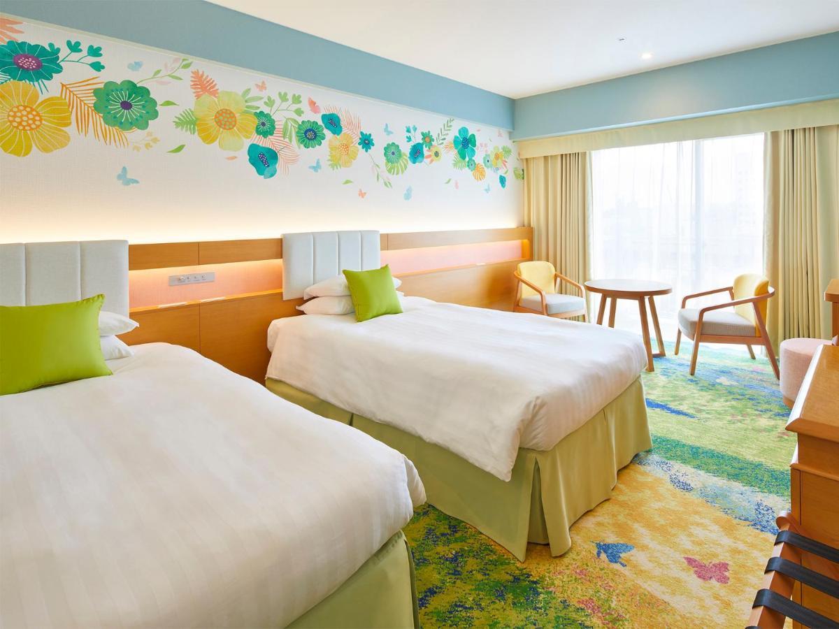 Отель Grand Nikko Tokyo Bay Maihama Ураясу Экстерьер фото The photo shows a brightly decorated hotel room featuring two twin beds with white linens and light green accents. Above the beds is a colorful floral mural that adds a cheerful touch to the space. There is a small table and chairs by the window, whi