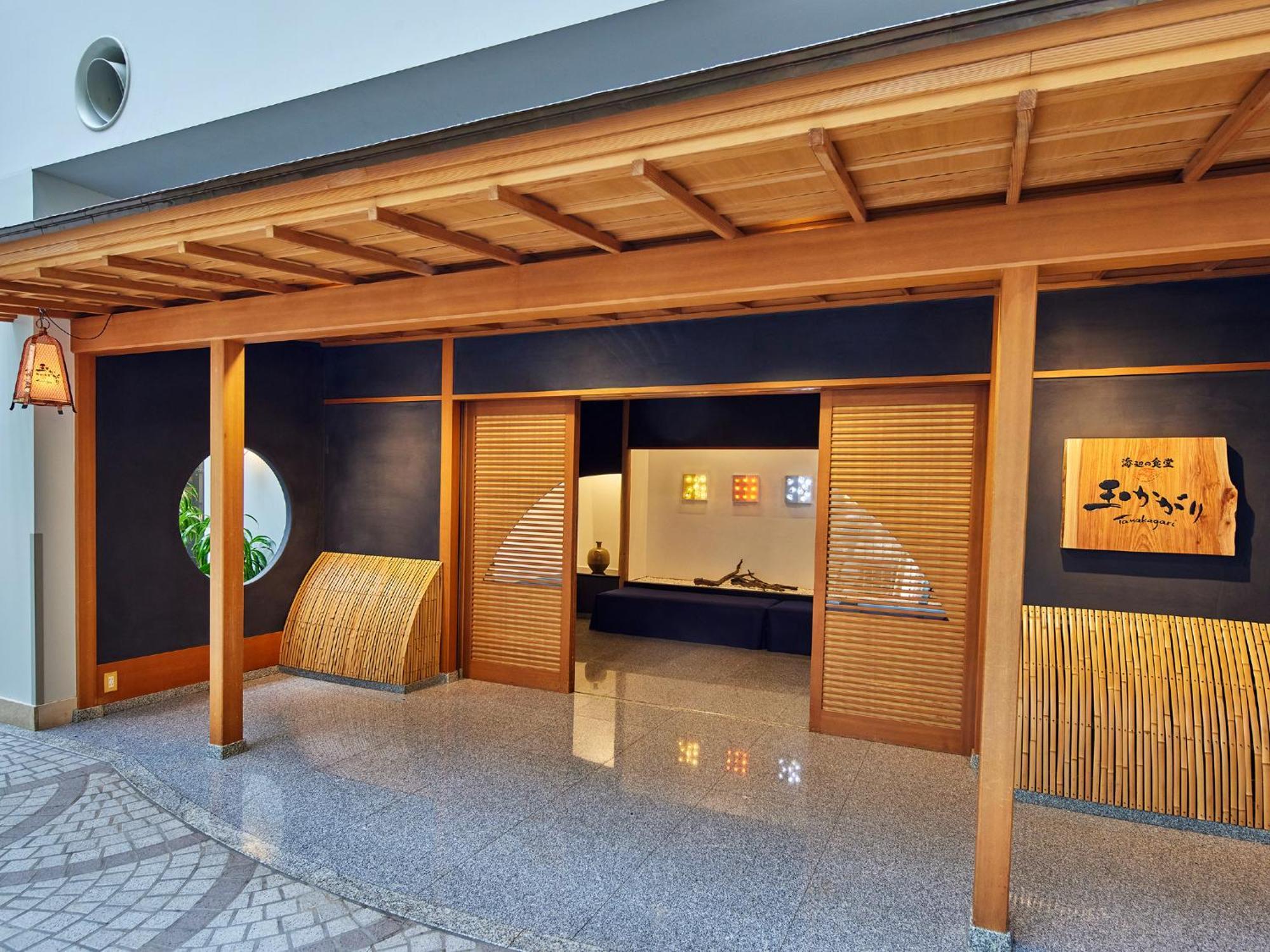 Отель Grand Nikko Tokyo Bay Maihama Ураясу Экстерьер фото The photo shows the entrance of a building, designed in a traditional Japanese style. It features a wooden structure with a large overhanging roof and sliding doors. The entrance is flanked by rounded windows, and there's a decorative sign with Japan