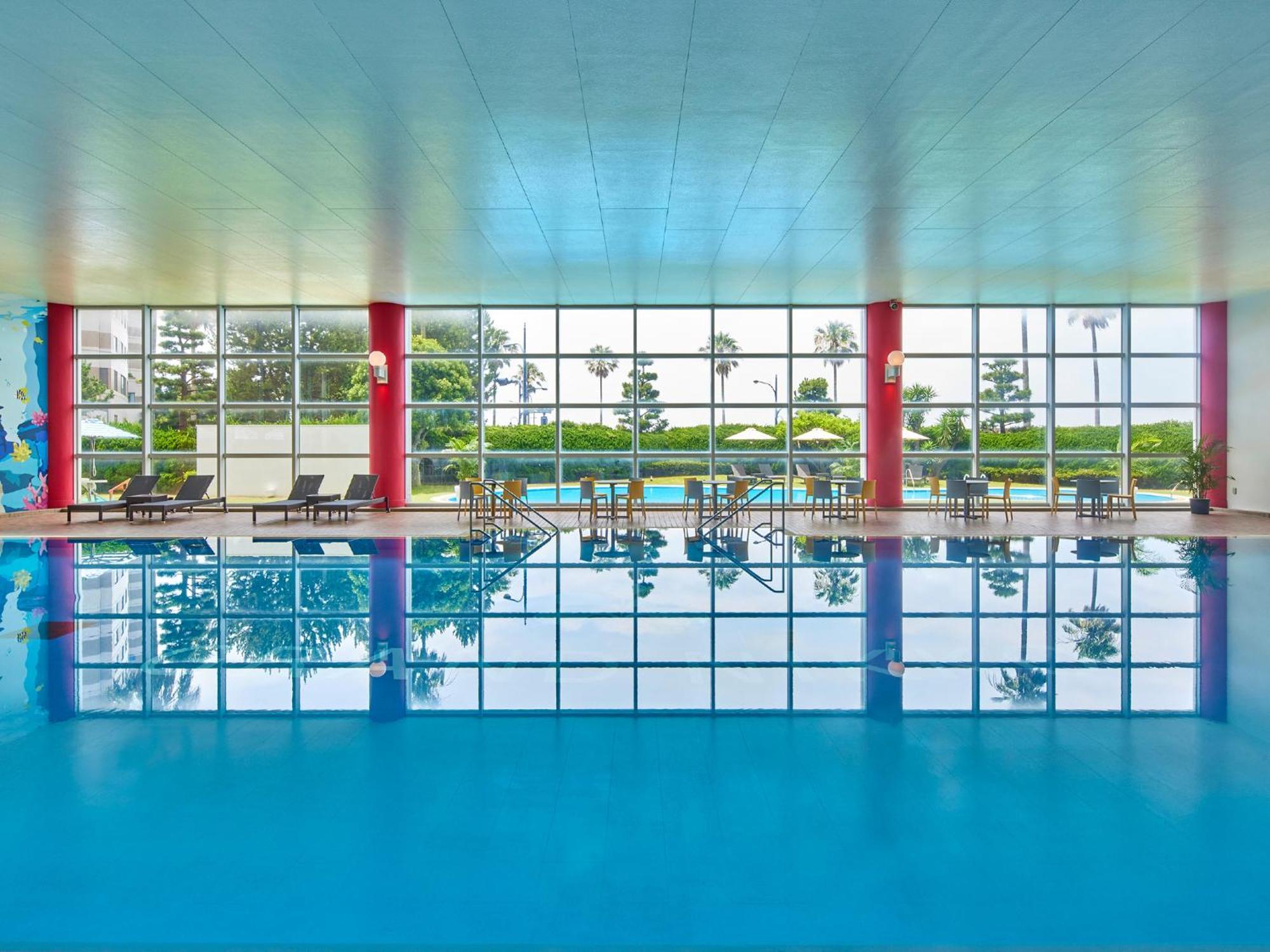 Отель Grand Nikko Tokyo Bay Maihama Ураясу Экстерьер фото The photo shows an indoor swimming pool with bright blue water. The pool area is spacious, characterized by large windows that allow natural light to flood in, creating a vibrant atmosphere. The walls are painted in a soft color, with accents of red.