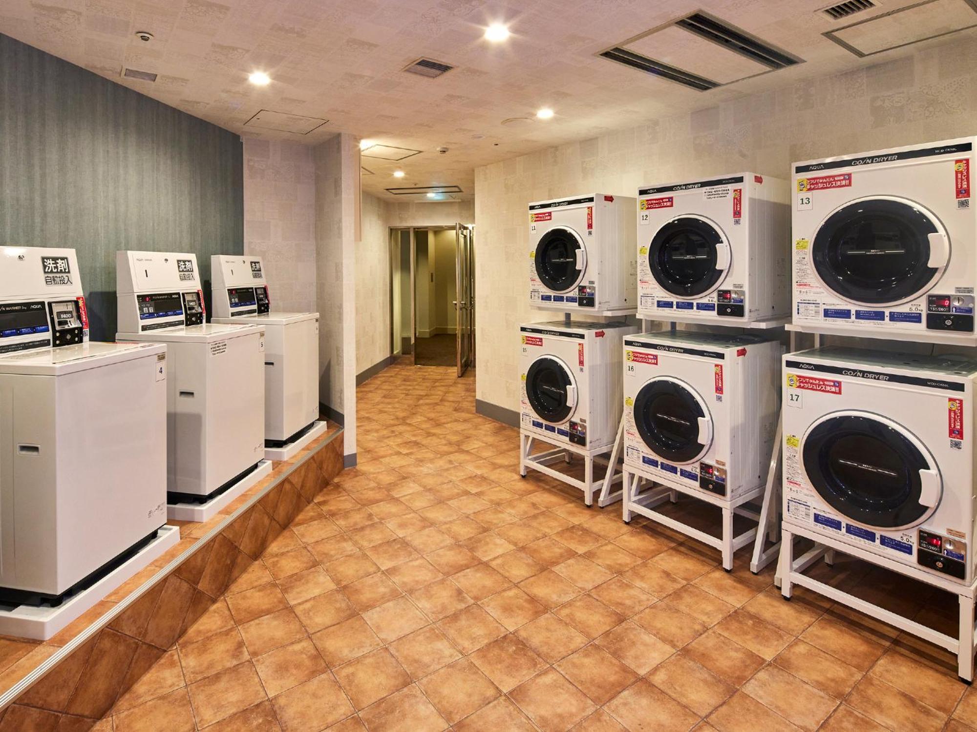 Отель Grand Nikko Tokyo Bay Maihama Ураясу Экстерьер фото The photo shows a laundry room with several washing machines and dryers. On the left side, there are five white washing machines, and on the right side, there are four dryers. The machines are arranged in a clean, tiled space with a neutral-colored w
